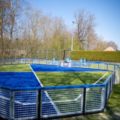 Moderna cancha deportiva vallada con césped azul y verde en Vakantiepark Bergumermeer, Frisia, Países Bajos.