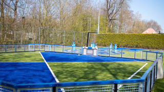 Moderna cancha deportiva vallada con césped azul y verde en Vakantiepark Bergumermeer, Frisia, Países Bajos.