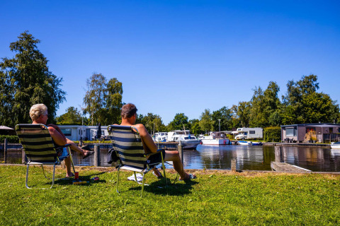 Due persone si rilassano su sedie vicino all’acqua al Vakantiepark Bergumermeer, Friesland, Paesi Bassi.