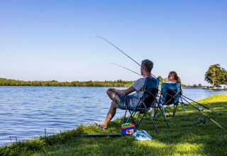 Zwei Menschen angeln entspannt am Seeufer im Vakantiepark Bergumermeer, Friesland, Niederlande.