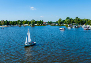 Zeilboot op een meer nabij Sumar, Friesland, Nederland, met groene bomen en boten in de verte