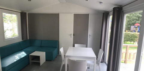 Helles Wohnzimmer in Lodge XL im Vakantiepark Bergumermeer, Niederlande, mit Sofa und Esstisch.