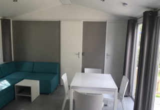 Helles Wohnzimmer in Lodge XL im Vakantiepark Bergumermeer, Niederlande, mit Sofa und Esstisch.