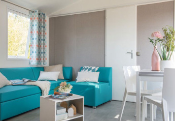 Luminoso salón moderno en la Lodge XL de Vakantiepark Bergumermeer, Países Bajos, con sofá azul y mesa blanca.