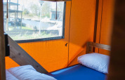 Vista interior de tienda Safari con cama individual, almohada y edredón en Vakantiepark Bergumermeer, Países Bajos.