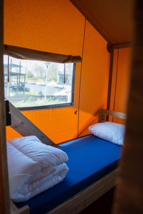 Vista interna di una tenda Safari con letto singolo, cuscino e piumone a Vakantiepark Bergumermeer, Paesi Bassi.