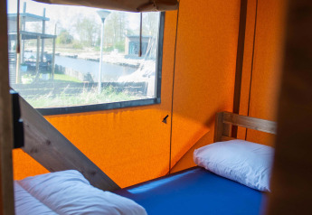 Indvendig udsigt af Safari-telt med enkeltseng, puder og dyne på Vakantiepark Bergumermeer i Holland.