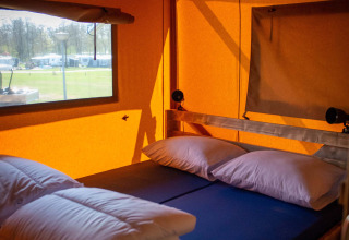 Interior view of a safari tent with double bed, pillows and duvets at Vakantiepark Bergumermeer, Netherlands.