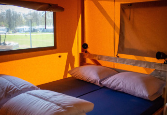 Innenaufnahme eines Safari-Zeltes mit Bett, Kissen und Decken im Vakantiepark Bergumermeer, Niederlande.