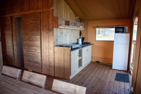 Indvendig udsigt over et safaritelthus ved Vakantiepark Bergumermeer med træmøbler og tekøkken.