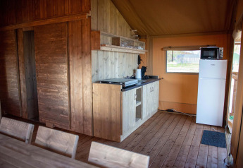 Indvendig udsigt over et safaritelthus ved Vakantiepark Bergumermeer med træmøbler og tekøkken.