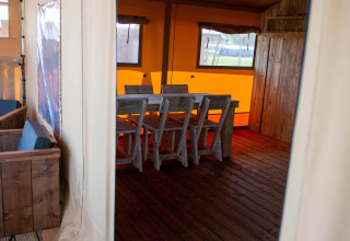 Eingang zum Safari-Zelt im Vakantiepark Bergumermeer in den Niederlanden, mit Holzboden und Sitzgruppe.