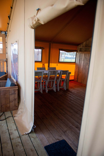 Eingang zum Safari-Zelt im Vakantiepark Bergumermeer in den Niederlanden, mit Holzboden und Sitzgruppe.