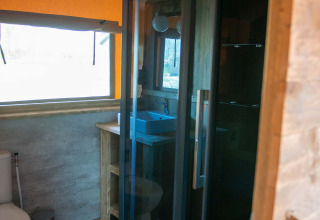 Bathroom inside a Safari tent at Vakantiepark Bergumermeer in the Netherlands, with shower and toilet.