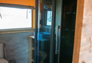 Salle de bain d'une tente Safari au Vakantiepark Bergumermeer, Pays-Bas, avec douche et toilettes.