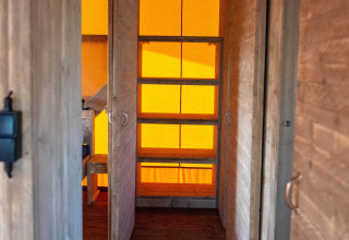 Interior view of a safari tent lodge with wooden walls and orange lighting at Bergumermeer, Netherlands.