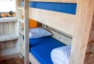 Køjeseng i en safaritelt-lodge på Vakantiepark Bergumermeer, Holland, med træinteriør og blå madrasser.