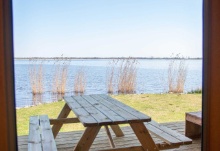 View from safari tent at Vakantiepark Bergumermeer, Netherlands, with picnic table and lakeside scenery.