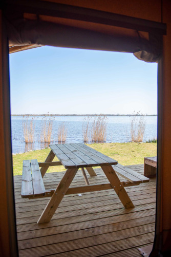 Blick aus dem Safari-Zelt im Vakantiepark Bergumermeer, Niederlande, auf Picknicktisch und See.