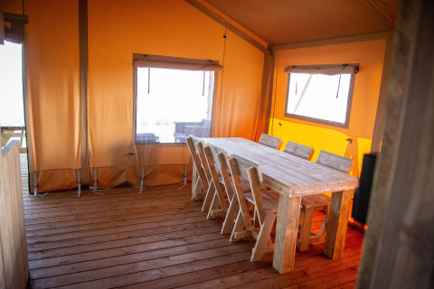 Interieur van een safaritentlodge met houten tafel bij Vakantiepark Bergumermeer in Nederland.