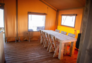 Indretning af en safariteltslodge med træbord og stole på Vakantiepark Bergumermeer i Holland.