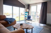 Salon lumineux dans la Waterlodge type 2 au Vakantiepark Bergumermeer, Pays-Bas, avec vue sur l’eau.