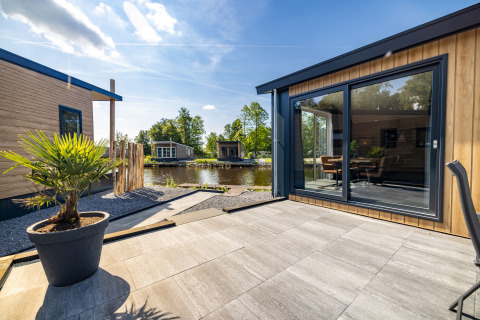 Outdoor terrace at Waterlodge type 2 featuring modern wood facade, large windows, and water views
