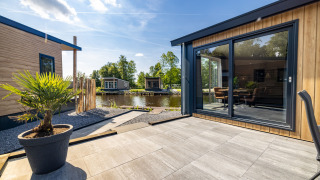 Terrasse extérieure au Waterlodge type 2 avec façade en bois moderne, grandes fenêtres et vue sur l’eau