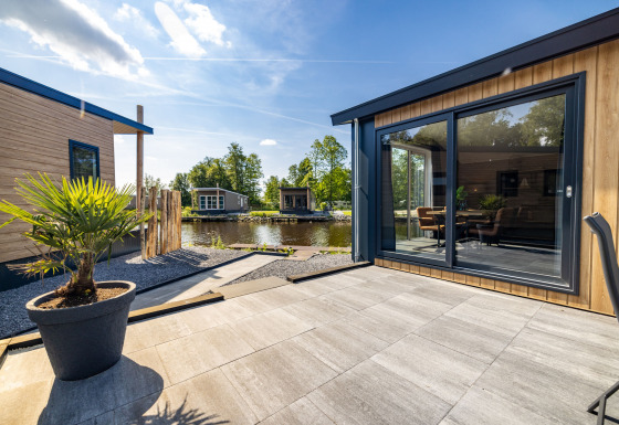 Außenterrasse der Waterlodge Typ 2 mit moderner Holzfassade, Blick auf Wasser und Sitzbereich