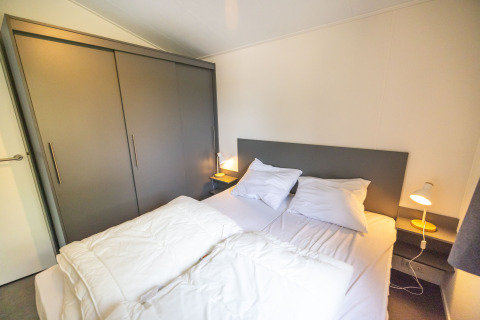 Camera da letto con letto matrimoniale, testiera grigia e armadi in Waterlodge tipo 2, Vakantiepark Bergumermeer.