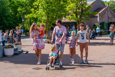 Familia disfruta de un día soleado en un parque vacacional con glamping, paseando al aire libre.