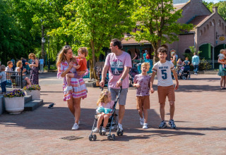 Family enjoying a sunny day at a holiday park offering glamping, walking together outdoors.