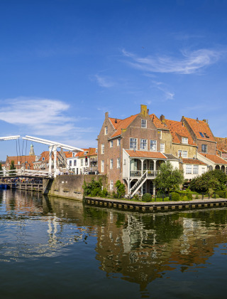 Foto eines Ferienparks mit Glamping, historischen Gebäuden und Brücke über einem ruhigen Kanal.