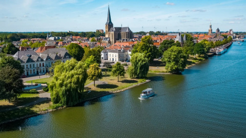 Blick auf eine malerische Stadt am Fluss mit Parks, Boot und Glamping-Urlaubspark im Hintergrund.