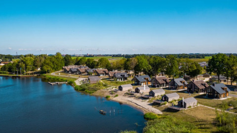 Parque vacacional con alojamientos glamping junto al lago, rodeado de árboles y paisajes naturales.