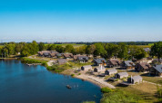 Holiday park with glamping accommodations by a lake, featuring cabins and scenic views of nature.