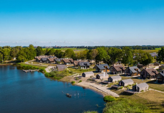 Holiday park with glamping accommodations by a lake, featuring cabins and scenic views of nature.