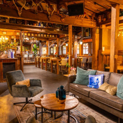 Acogedora sala en parque vacacional con interiores de madera, sofás cómodos y mesas para relajarse.