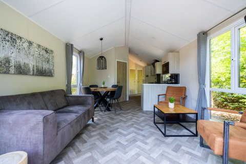 Salón moderno en Forest Cottage, Recreatiepark de Paalberg, Países Bajos, con ventanales y decoración acogedora.