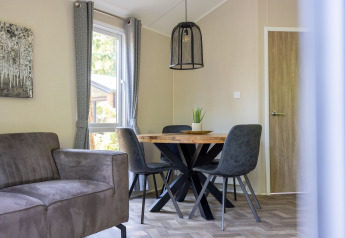 Moderne stue i Forest Cottage på Recreatiepark de Paalberg med spisebord, stole og sofa i neutral stil.