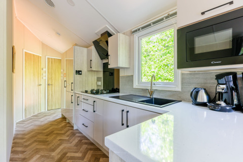 Cocina moderna con ventana al bosque, cafetera y microondas en Forest Cottage, Recreatiepark de Paalberg.