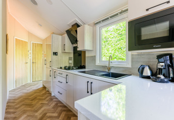 Cuisine moderne avec fenêtre, cafetière et micro-ondes au Forest Cottage, Recreatiepark de Paalberg.