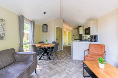 Sala de estar y cocina moderna en Forest Cottage, Recreatiepark de Paalberg, Países Bajos, con decoración acogedora.