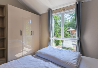 Dormitorio en Forest Cottage en Recreatiepark de Paalberg, Países Bajos, con vista a un bosque verde.