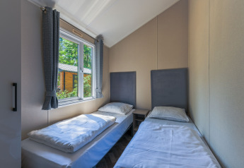 Soveværelse i Forest Cottage på Recreatiepark de Paalberg i Holland med to enkeltsenge og vindue.