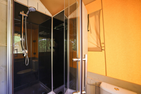 Ducha y baño modernos en una tienda glamping del Recreatiepark de Paalberg, Países Bajos, con paredes naranjas.