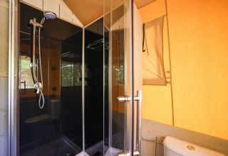 Ducha y baño modernos en una tienda glamping del Recreatiepark de Paalberg, Países Bajos, con paredes naranjas.