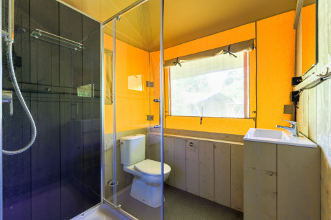 Baño moderno en una tienda glamping en Recreatiepark de Paalberg, Países Bajos, con ducha y ventana grande.