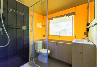 Baño moderno en una tienda glamping en Recreatiepark de Paalberg, Países Bajos, con ducha y ventana grande.