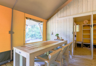 Interieur van een luxe glampingtent met houten meubilair op Recreatiepark de Paalberg, Nederland.